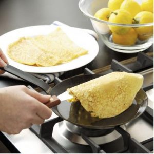 persona haciendo crepes en una sartén de crepes 