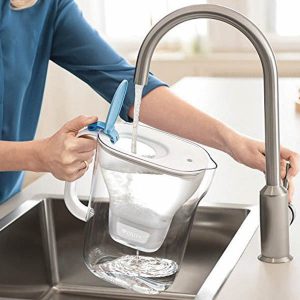 persona llenando una jarra de agua filtrada 